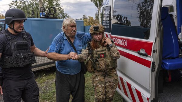 Police officers help Mykola Puzyk, 70, who lost his wife Tetiana Puzyk, 68, to move from an armored car to a ambulance from the village of Yarova. September 9, 2025. - Sputnik International