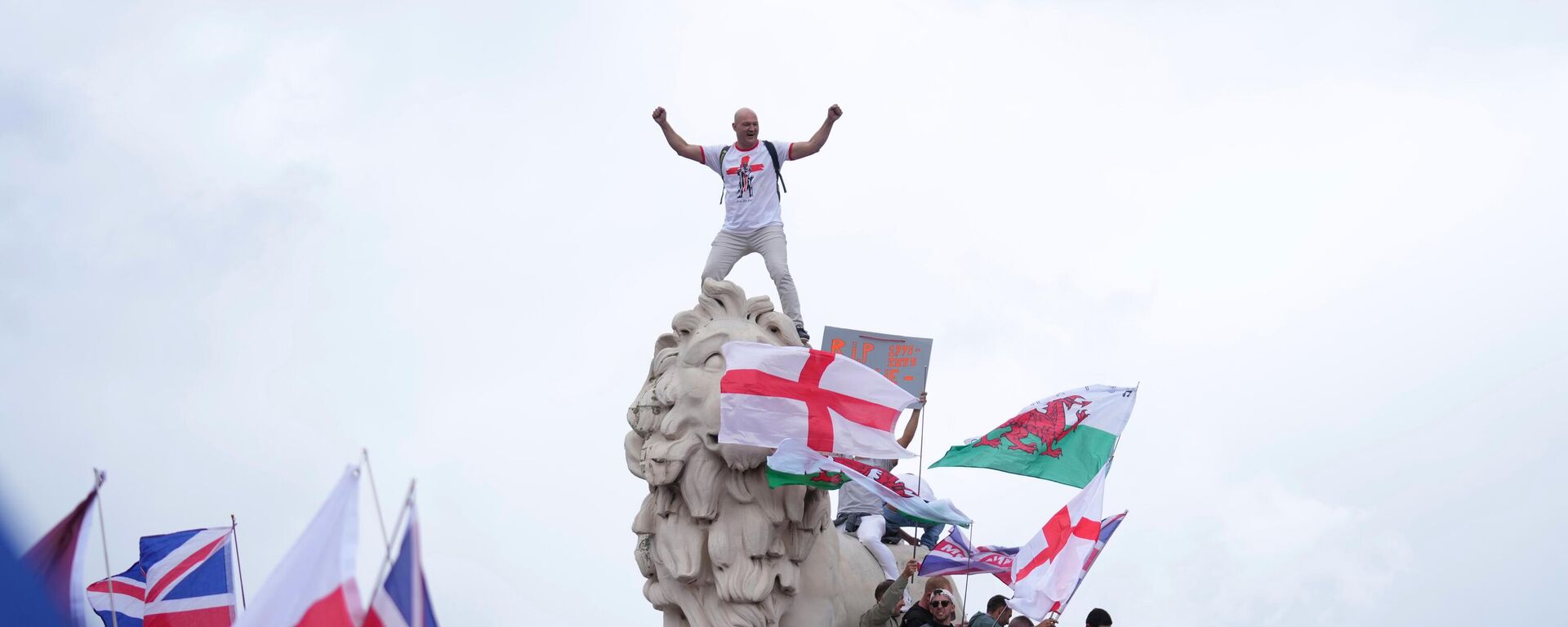 A demonstrator stands on the head of the South Bank lion that sits on the side of the Westminster Bridge, during a Tommy Robinson-led Unite the Kingdom march and rally in London - Sputnik International, 1920, 13.09.2025