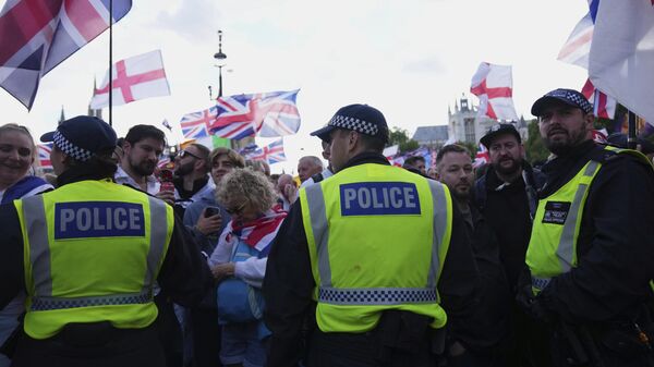 Police officers form a line in front of demonstrators from the Tommy Robinson-led Unite the Kingdom march and rally near Westminster, London, Saturday Sept. 13, 2025.  - Sputnik International