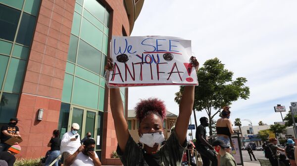A woman holds a sign addressing ANTIFA at a protest in Los Angeles - Sputnik International