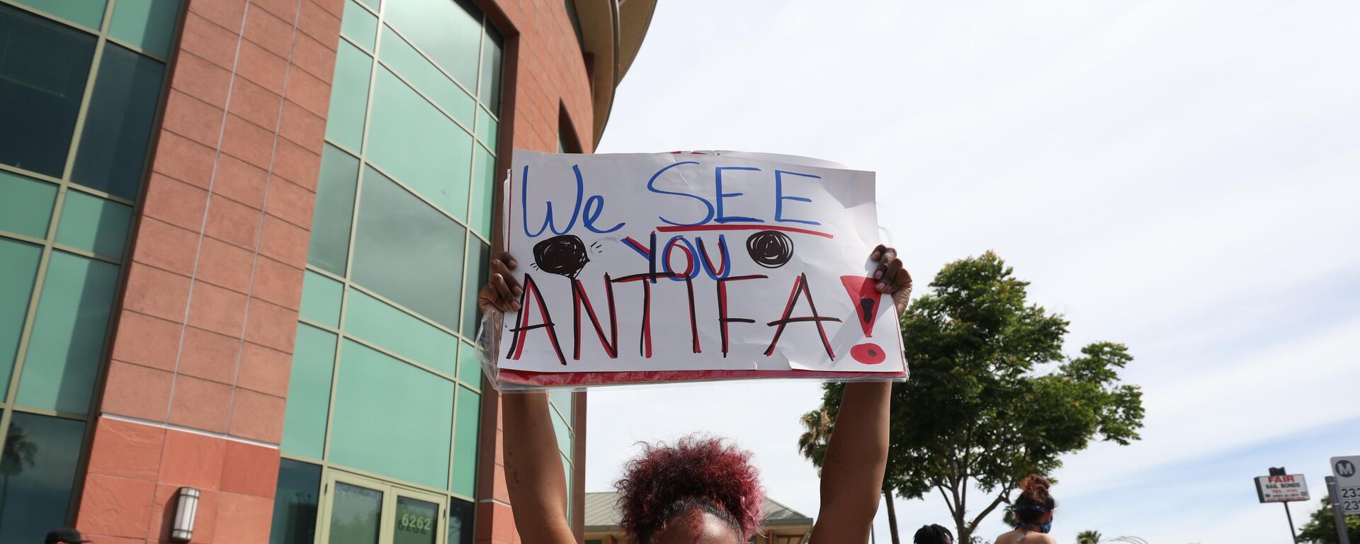A woman holds a sign addressing ANTIFA at a protest in Los Angeles - Sputnik International, 1920, 23.09.2025