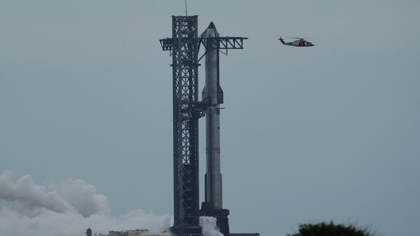 A helicopter passes SpaceX's mega rocket Starship as it is prepared for a test flight from Starbase, Texas, Monday, Aug. 25, 2025 - Sputnik International