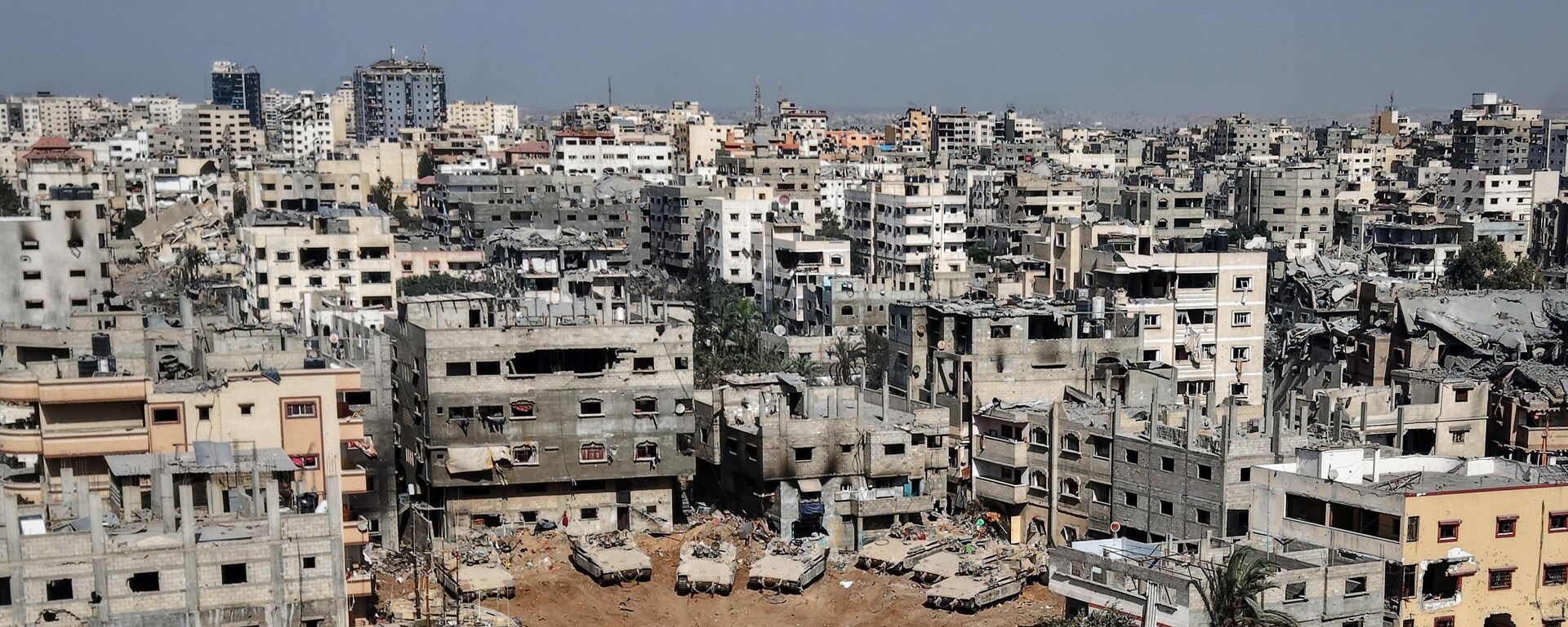 This aerial picture taken during a media tour organised by the Israeli army, shows Israeli army tanks and armoured personnel carriers stationed amid war-damaged buildings in the vicinity of the Jordanian Field Hospital in Gaza City, Friday, Oct. 3, 2025.  - Sputnik International, 1920, 09.10.2025