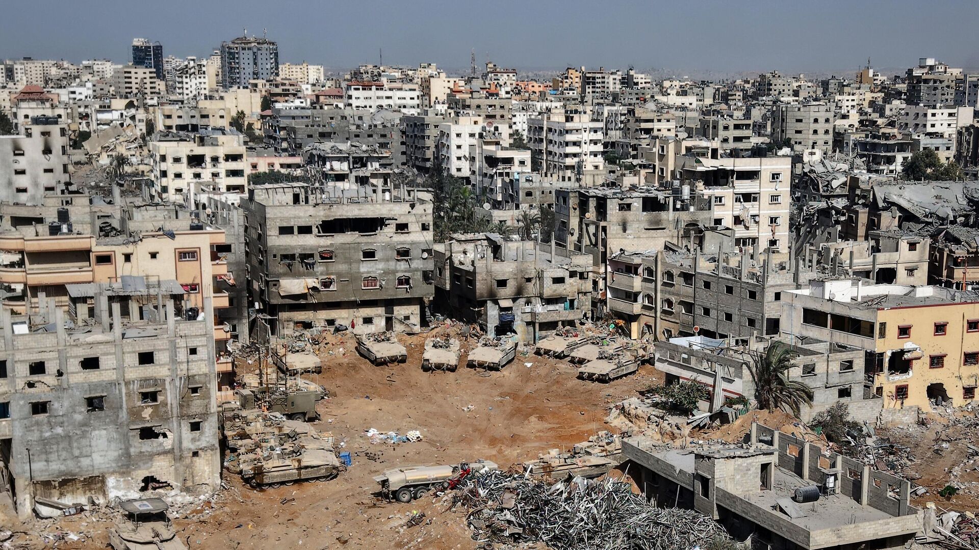 This aerial picture taken during a media tour organised by the Israeli army, shows Israeli army tanks and armoured personnel carriers stationed amid war-damaged buildings in the vicinity of the Jordanian Field Hospital in Gaza City, Friday, Oct. 3, 2025.  - Sputnik International, 1920, 15.11.2025