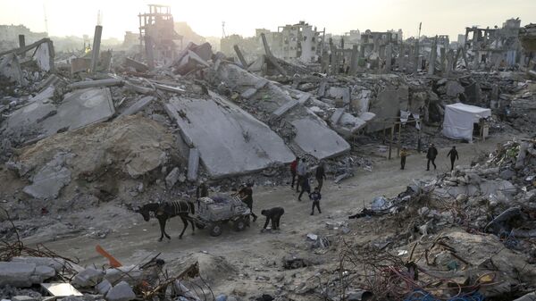 People walk amid the destruction caused by the Israeli air and ground offensive in Jabaliya, Gaza Strip, on Tuesday, Feb. 18, 2025 - Sputnik International