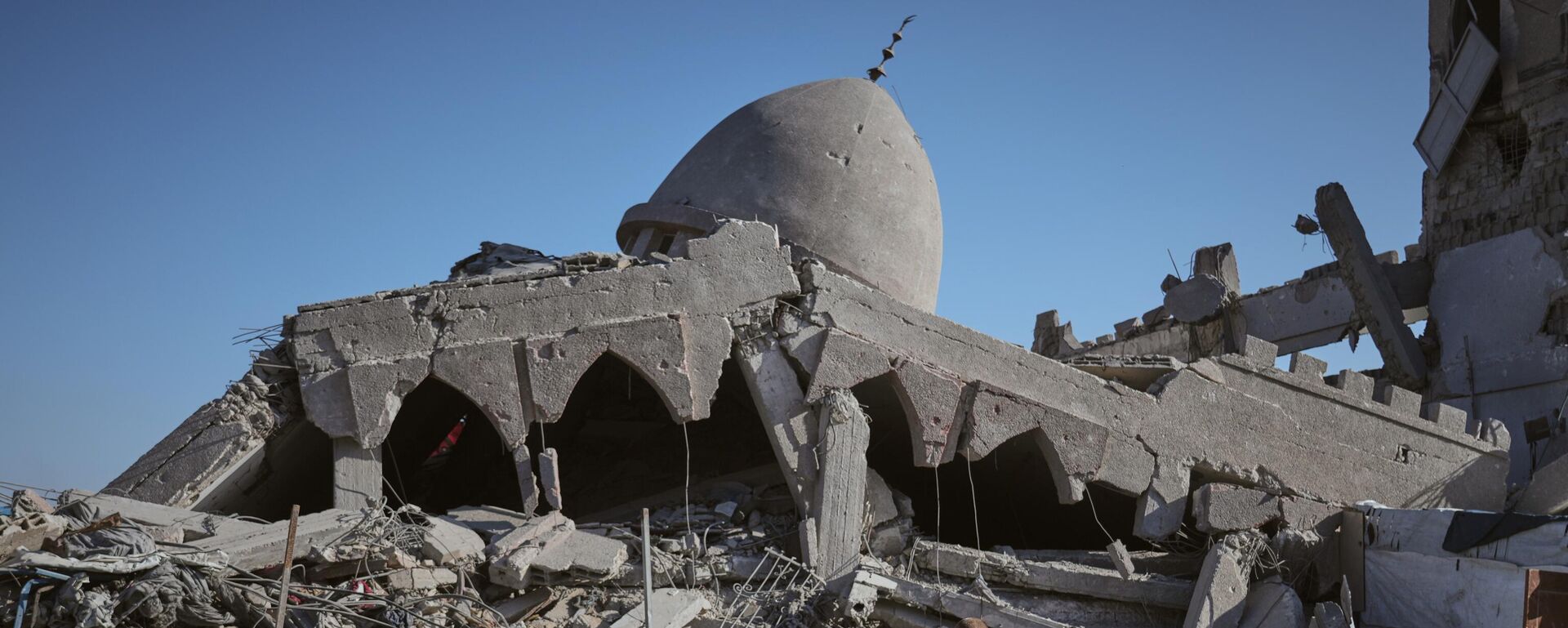 A Palestinian woman carrying her child walks past a destroyed mosque in Gaza City Sunday, Oct. 26, 2025.  - Sputnik International, 1920, 18.11.2025