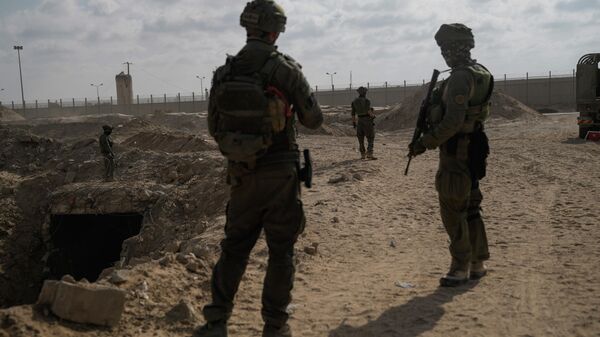 Israeli soldiers take up positions next to an entrance of a tunnel which the military says Hamas militants used in the southern Gaza Strip. - Sputnik International