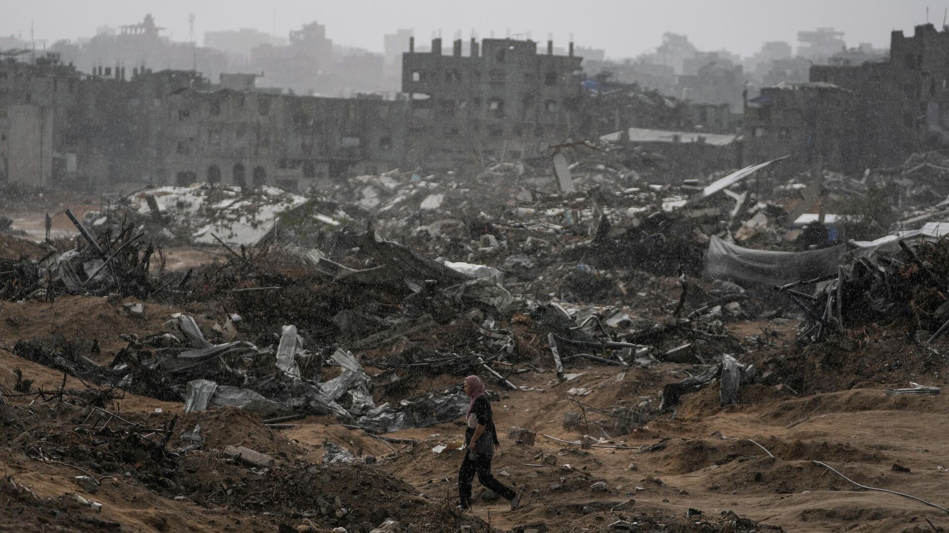 A Palestinian woman walks through a rainstorm past buildings destroyed in Israeli strikes in the Sheikh Radwan neighborhood of Gaza City, Friday, Nov. 14, 2025.  - Sputnik International, 1920, 15.11.2025
