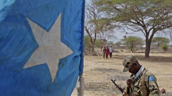 A soldier from the Somalian transitional government forces looks down, with a Somalian flag, left,  during a patrol of the border town of Dhobley, Somalia, Sunday, July 24, 2011 - Sputnik International