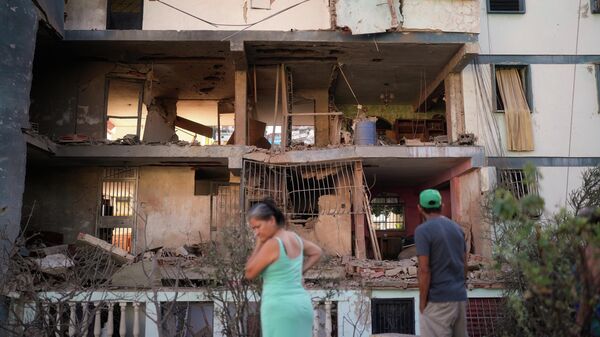 Residents look at a damaged apartment complex that neighbors say was hit during US strikes to capture Venezuelan President Nicolás Maduro, in Catia La Mar, Venezuela, Sunday, Jan. 4, 2026.  - Sputnik International