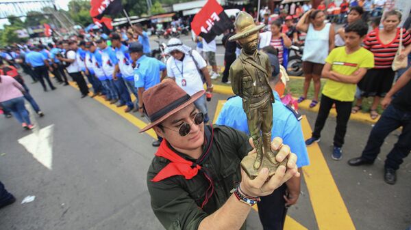 A supporter of the Sandinista National Liberation Front holds a statue representing founder Gen. Augusto Cesar Sandino - Sputnik International