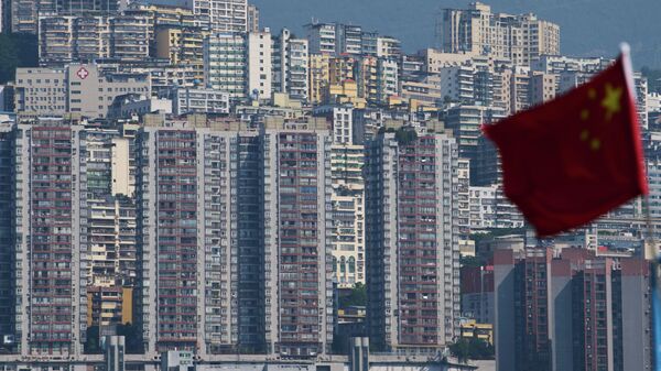 A Chinese national flag flutters against the high-rise residential buildings in Wushan county, in southwest China's Chongqing Municipality - Sputnik International