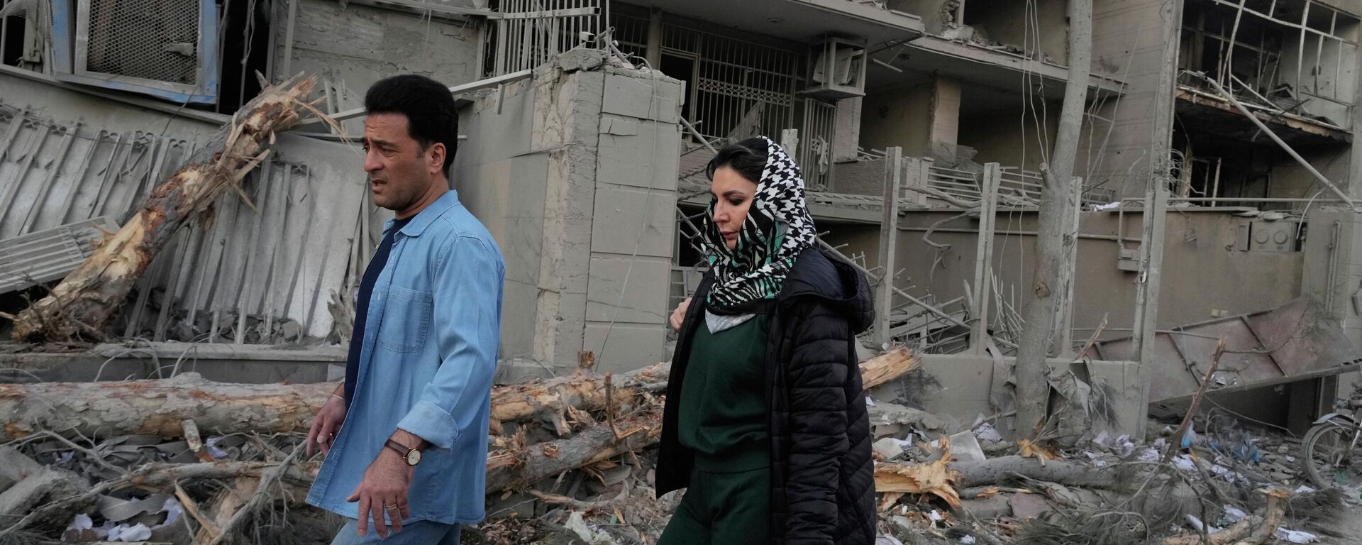People walk past buildings damaged during a strike on a police station during ongoing, joint U.S.-Israeli military attacks in Tehran, Iran, Monday, March 2, 2026. - Sputnik International, 1920, 02.03.2026