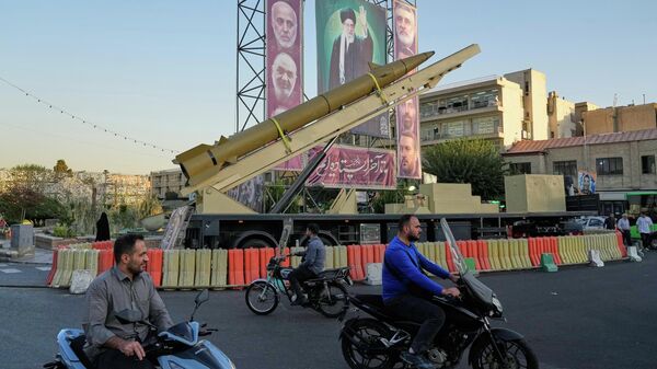 People drive past a domestically-built missile Khaibar-buster, and banners showing portraits of the now-late Iranian Supreme Leader Ayatollah Ali Khamenei, displayed in a military exhibition commemorating the anniversary of the start of the 1980-88 Iraq-Iran war, in Tehran, Sept. 25, 2025.  - Sputnik International