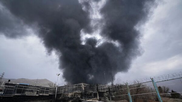 A thick plume of smoke rises from an oil storage facility hit by a U.S.-Israeli strike late Saturday in Tehran, Iran, March 8, 2026.  - Sputnik International