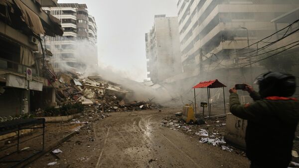A man photographs the rubble of buildings destroyed in an Israeli airstrike in Dahiyeh, Beirut's southern suburbs, Lebanon, Sunday, March 15, 2026. (AP Photo/Hassan Ammar) - Sputnik International