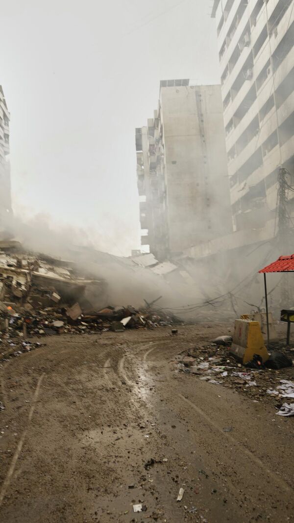 A man photographs the rubble of buildings destroyed in an Israeli airstrike in Dahiyeh, Beirut's southern suburbs, Lebanon, Sunday, March 15, 2026. (AP Photo/Hassan Ammar) - Sputnik International