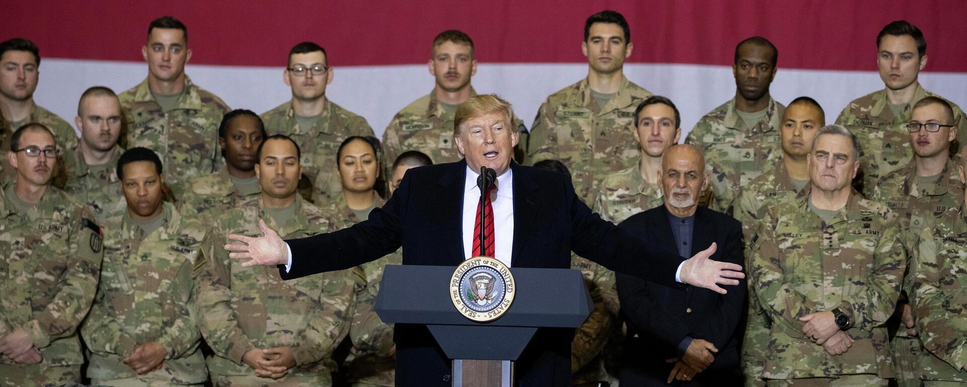 President Donald Trump, center, with Afghan President Ashraf Ghani and Joint Chiefs Chairman Gen. Mark Milley, behind him at right, while addressing members of the military during a surprise Thanksgiving Day visit, Thursday, Nov. 28, 2019, at Bagram Air Field, Afghanistan - Sputnik International, 1920, 19.03.2026