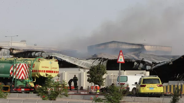 Firefighters work as smoke rises outside a damaged warehouse in an industrial area in Al Rayyan, Qatar, following an Iranian strike, Sunday, March 1, 2026. (AP Photo) - Sputnik International