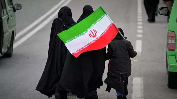 Two women and a child holding an Iranian flag walk toward the Imam Khomeini Grand Mosque to attend Friday prayers in Tehran, Iran, Friday, March 20, 2026.  - Sputnik International