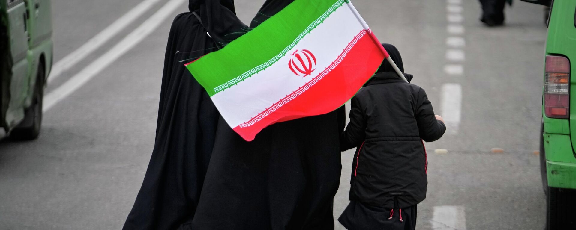 Two women and a child holding an Iranian flag walk toward the Imam Khomeini Grand Mosque to attend Friday prayers in Tehran, Iran, Friday, March 20, 2026.  - Sputnik International, 1920, 12.06.2026