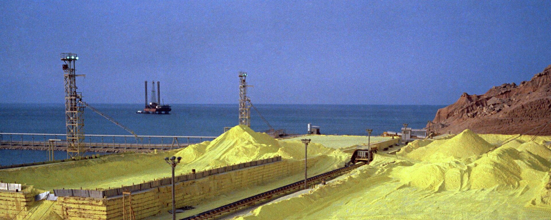Yellow sulphur, a byproduct of petrochemical refinement, contrasts with the blue sea at Kharg Island, Iran, July 1971.  - Sputnik International, 1920, 26.03.2026
