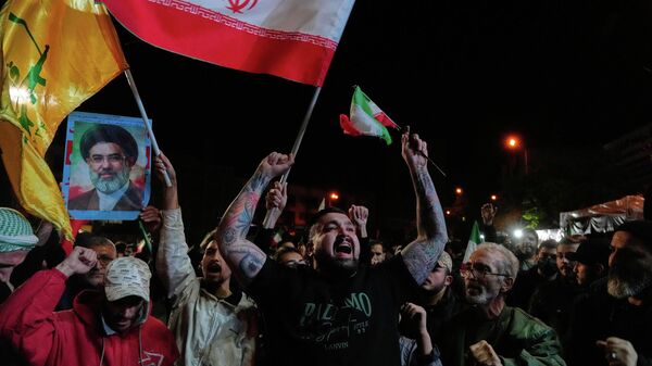 Iranians chant slogans as they hold Iranian flags and a poster of the Supreme Leader Ayatollah Mojtaba Khamenei in a gathering after announcement of a two-week ceasefire in the war with the United States and Israel, at the Enqelab-e-Eslami, or Islamic Revolution, Square, in Tehran, Iran, Wednesday, April 8, 2026.  - Sputnik International