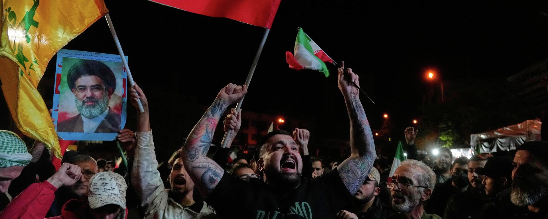 Iranians chant slogans as they hold Iranian flags and a poster of the Supreme Leader Ayatollah Mojtaba Khamenei in a gathering after announcement of a two-week ceasefire in the war with the United States and Israel, at the Enqelab-e-Eslami, or Islamic Revolution, Square, in Tehran, Iran, Wednesday, April 8, 2026.  - Sputnik International, 1920, 08.04.2026