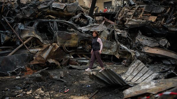 A resident walks near charred cars, at the site of Wednesday's Israeli airstrike, in Beirut, Lebanon, Friday, April 10, 2026. - Sputnik International
