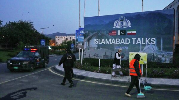 A worker cleans the street as police officers walks towards their vehicle outside a media center close to Serena Hotel, the venue for the U.S. Iran officials meeting, in Islamabad, Pakistan, Sunday, April 12, 2026. - Sputnik International