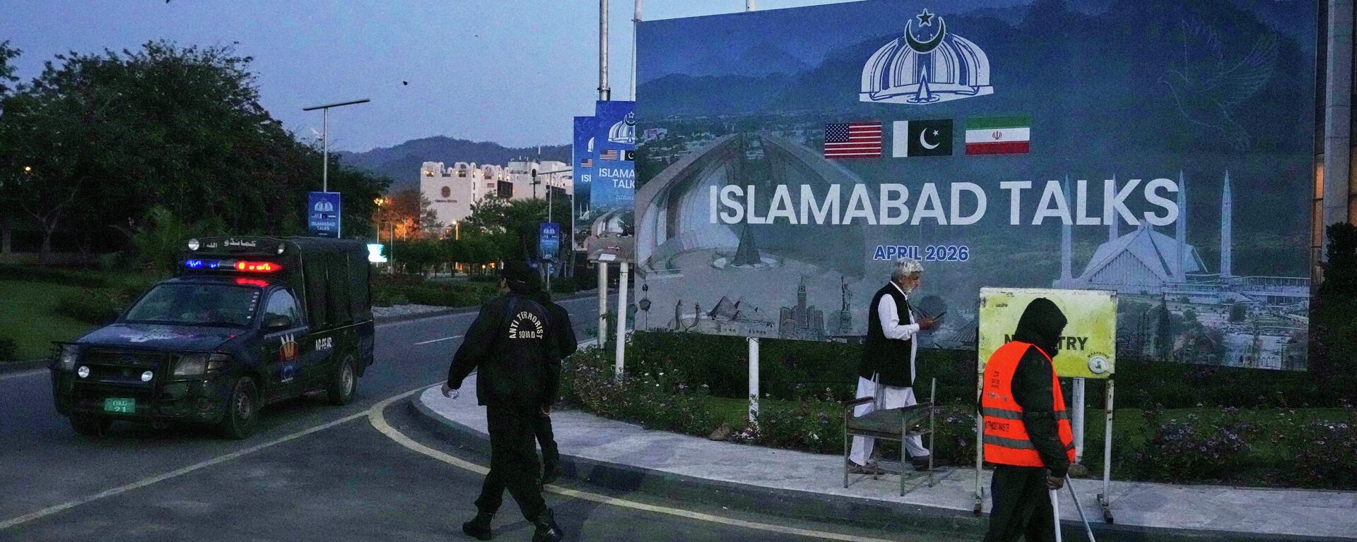 A worker cleans the street as police officers walks towards their vehicle outside a media center close to Serena Hotel, the venue for the U.S. Iran officials meeting, in Islamabad, Pakistan, Sunday, April 12, 2026. - Sputnik International, 1920, 12.04.2026