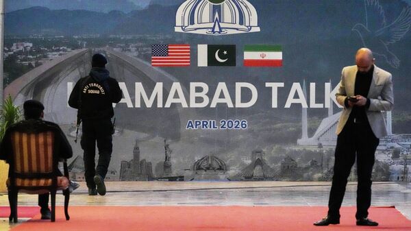 A security guard walks past a billboard  of the U.S. Iran talks outside a media center set up for the coverage of the U.S. Iran official meeting, in Islamabad, Pakistan, April 12, 2026.  - Sputnik International