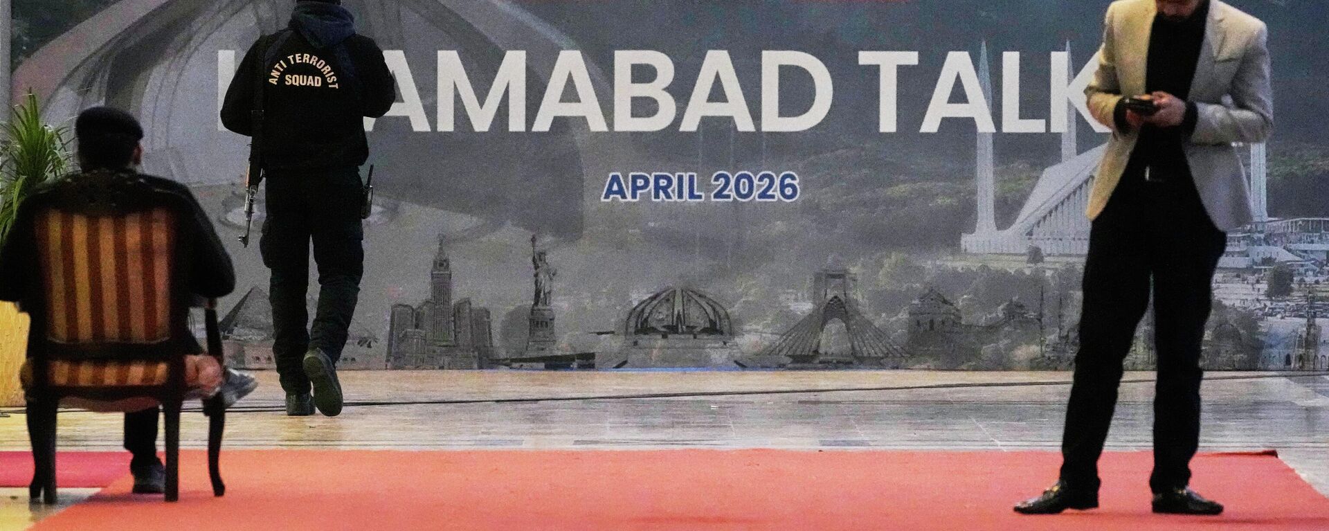 A security guard walks past a billboard  of the U.S. Iran talks outside a media center set up for the coverage of the U.S. Iran official meeting, in Islamabad, Pakistan, April 12, 2026.  - Sputnik International, 1920, 12.04.2026