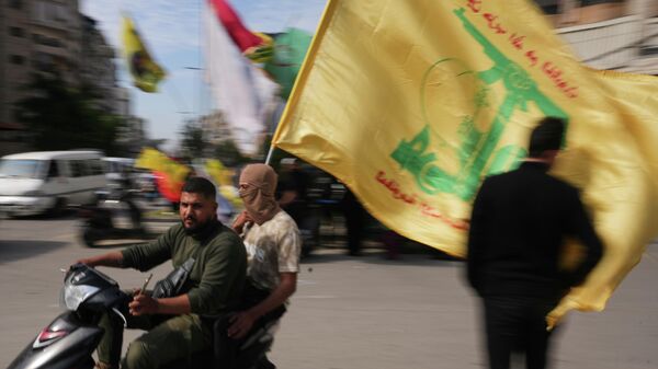 Men ride a scooter while waving a Hezbollah flag during a small gathering in Dahiyeh, Beirut's southern suburbs, Lebanon, Saturday, April 25, 2026. - Sputnik International