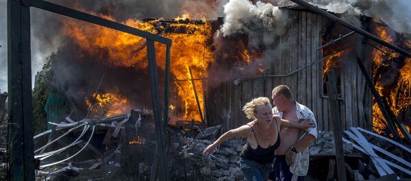 Local residents flee from a burning home hit by an air strike by the Ukrainian armed forces in Lugansk. Local residents flee from a burning home hit by an air strike by the Ukrainian armed forces in Lugansk. - Sputnik International