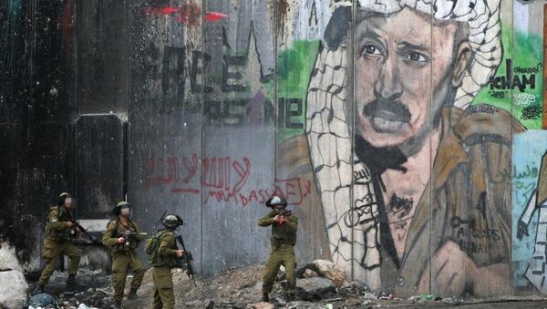 Israeli troops advance past a mural of the late Palestinian leader Yasser Arafat during clashes after a funeral in the Qalandia refugee camp near the West Bank city of Ramallah, Friday, Nov. 29, 2013. Palestinians buried Mahmud Awad, 22, who died of his injuries after he was shot during clashes with Israeli troops in March. - Sputnik International