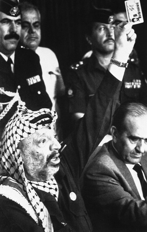 PLO Chairman Yasser Arafat waves one of the plastic identity cards Israel has imposed on Gaza Strip Palestinians working in Israel, in Amman, Jordan on August 22, 1989. He asked the US to condemn the card as a form of discrimination - Sputnik International
