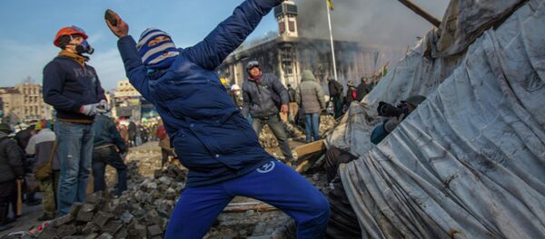 A protester throws stone on Maidan square in Kiev, Ukraine, Feb 19, 2014 - Sputnik International
