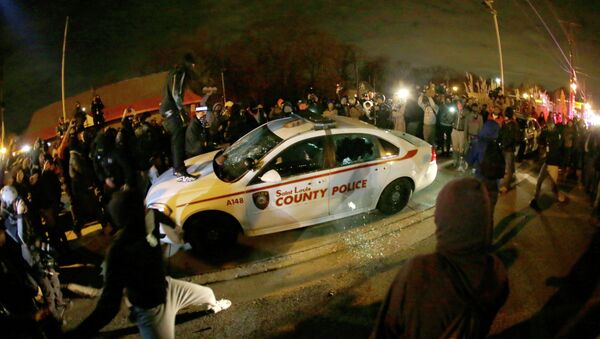 A protester squirts lighter fluid on a police car as the car windows are shuttered near the Ferguson Police Department - Sputnik International