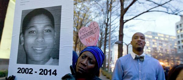 A protester holds a picture of Tamir Rice, the boy fatally shot by a rookie police officer, during a protest in response to a grand jury's decision in Ferguson to not indict police officer Darren Wilson. Protesters across the U.S. have walked off their jobs or away from classes in support of the Ferguson protesters. Rice's death has also sparked community demonstrations against police shootings. - Sputnik International