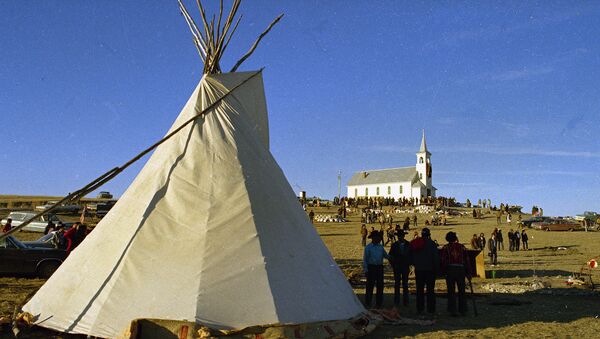 A teepee is seen with Wounded Knee Church in the background, at Wounded Knee in the Pine Ridge reservation, S.D., date unknown. Wounded Knee is the site of the massacre of 146 Lakota Sioux men, women and children, by the U.S. Army in 1890 - Sputnik International