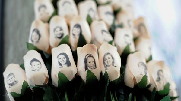 In this Jan. 14, 2013 file photo, white roses with the faces of victims of the Sandy Hook Elementary School shooting are attached to a telephone pole near the school on the one-month anniversary of the shooting that left 26 dead in Newtown, Conn. - Sputnik International