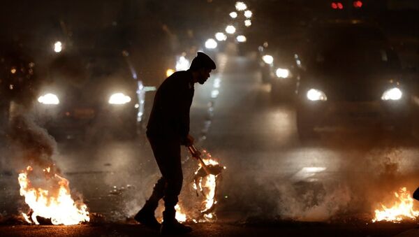 A police officer pulls a burning tyre from a highway that Bahraini anti-government protesters blocked near Jidhafs, Bahrain - Sputnik International