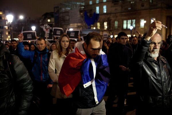 A man stands wrapped in a French flag as people hold up pens and a posters reading - Sputnik International