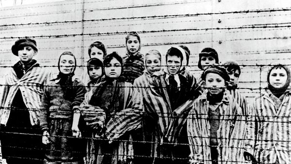 A group of children wearing concentration camp uniforms behind barbed wire fencing in the Oswiecim (Auschwitz) Nazi concentration camp - Sputnik International
