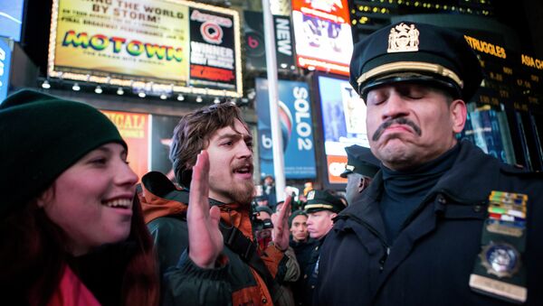 A NYPD policeman (R) reacts next to people protesting against the Staten Island death of Eric Garner during an arrest in July, at midtown Manhattan in New York December 3, 2014 - Sputnik International