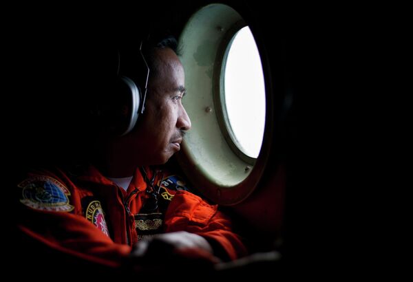 A member of an Indonesian Hercules C130 aircrew watches through a window while monitoring the Belitung Timur sea during search operations for AirAsia flight QZ8501 near Belitung island. A member of an Indonesian Hercules C130 aircrew watches through a window while monitoring the Belitung Timur sea during search operations for AirAsia flight QZ8501 near Belitung island. - Sputnik International
