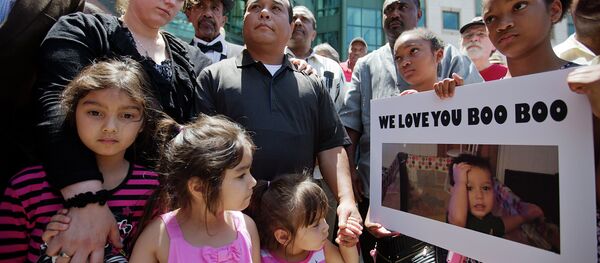 Alecia and Boun Khan Phonesavanh, from rear left, the parents of 19-month-old Bounkham Phonesavanh who was severely burned by a flash grenade during a SWAT drug raid, attend a vigil with their daughters outside Grady Memorial Hospital where he is undergoing treatment, Monday, June 2, 2014, in Atlanta. Alecia and Boun Khan Phonesavanh, from rear left, the parents of 19-month-old Bounkham Phonesavanh who was severely burned by a flash grenade during a SWAT drug raid, attend a vigil with their daughters outside Grady Memorial Hospital where he is undergoing treatment, Monday, June 2, 2014, in Atlanta. - Sputnik International