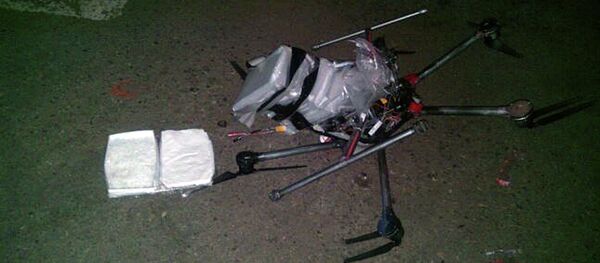 In this image released by the Tijuana Municipal Police on Wednesday Jan. 21, 2015, a drone loaded with packages containing methamphetamine lies on the ground after it crashed into a supermarket parking lot in the city of Tijuana on Tuesday Jan. 20, 2015. - Sputnik International