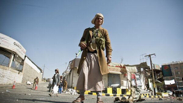 A Houthi Shiite Yemeni stands guard in front of a building damaged during recent clashes near the presidential palace in Sanaa, Yemen, Tuesday, Jan. 20, 2015. - Sputnik International
